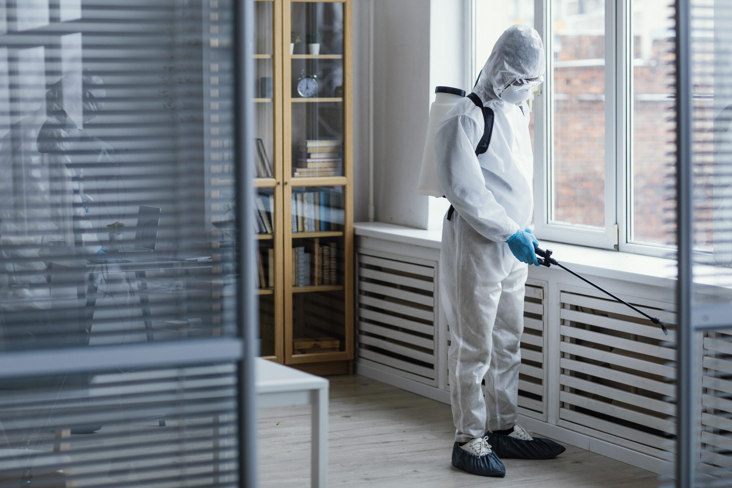 Person in protective gear disinfecting a biohazard area, emphasizing mold remediation and safety in Southwest Florida.