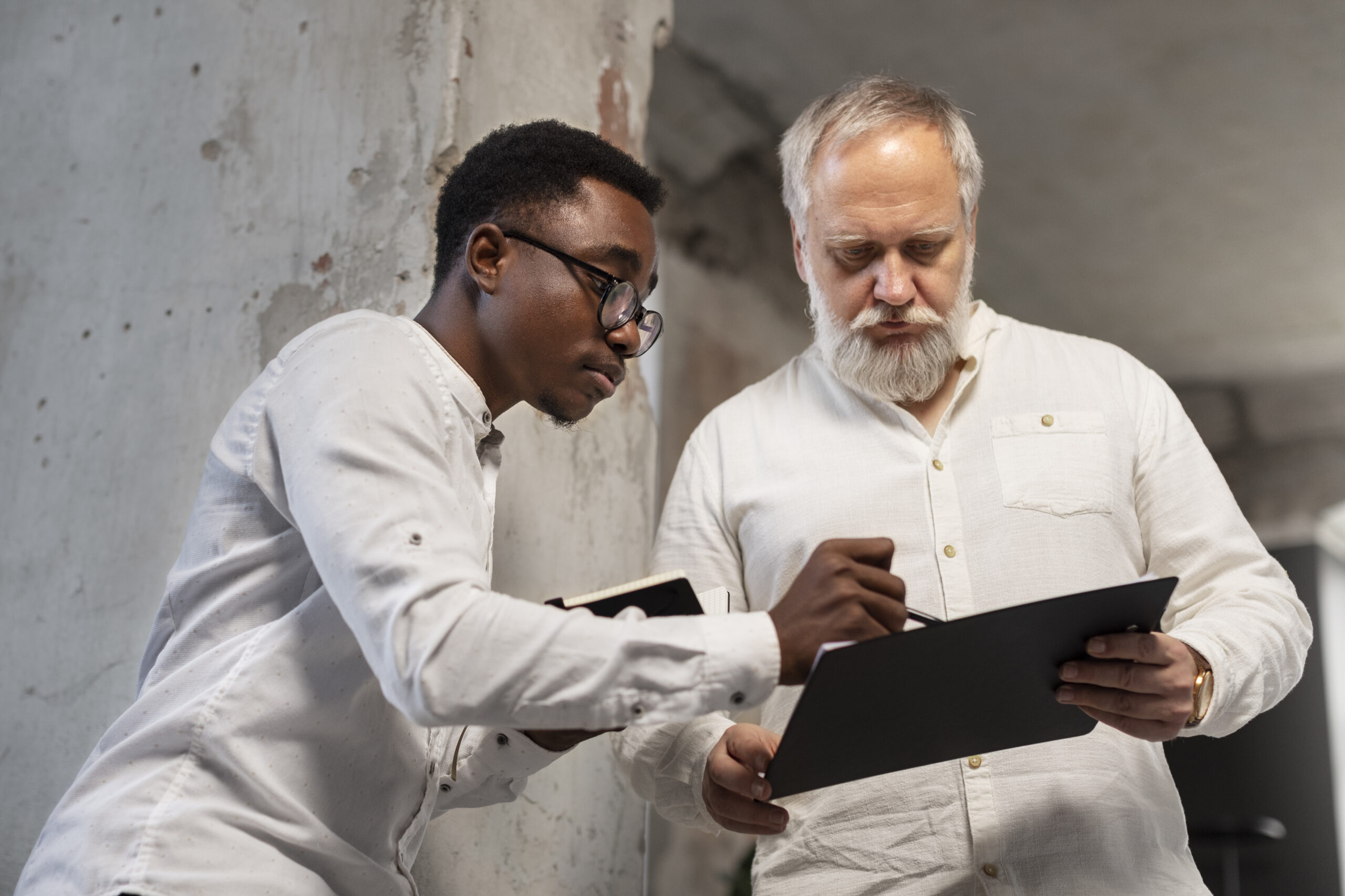 Two professionals discussing mold inspection details in an office setting, one taking notes on a clipboard, emphasizing collaboration in mold detection services.
